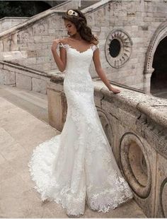 a woman in a wedding dress leaning on a stone wall