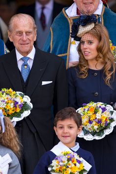 the queen and prince are standing next to each other with flowers in their lapels