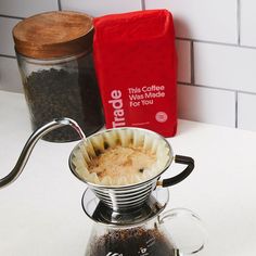 a coffee pot filled with liquid sitting on top of a counter next to a bag of coffee