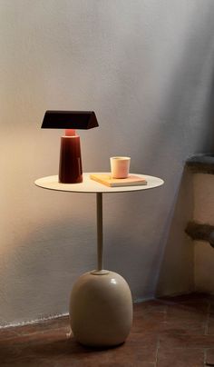 a small table with a lamp on it next to stairs and a chair in the background