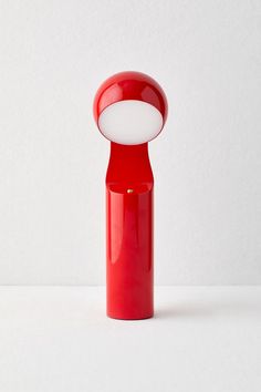 a red vase with a white light in it's center on a white surface