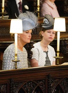 two women sitting next to each other in front of candles and wearing hats with feathers on them