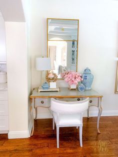 a white desk with flowers on it and a mirror in the corner next to it