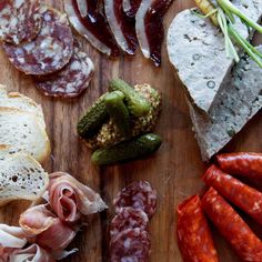 a wooden cutting board topped with meats and bread