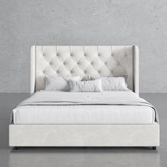 a bed with white linens and pillows in a gray room next to a concrete wall