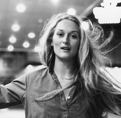 a black and white photo of a woman with her hair blowing in the wind,