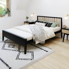 a bed sitting on top of a wooden floor next to a white and black rug