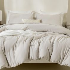 an unmade bed with white sheets and pillows