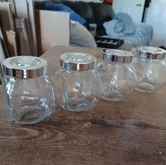 four glass jars sitting on top of a wooden table