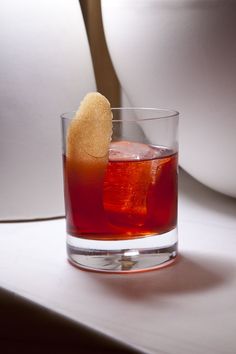 a close up of a drink in a glass with a cookie on the rim next to it