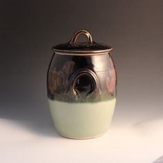 a brown and green ceramic jar sitting on top of a table