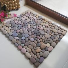 there is a rug made out of rocks on the floor next to a vase with flowers