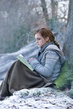 a woman sitting in the snow reading a book