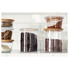 three glass containers filled with food on top of a white tiled counter next to each other