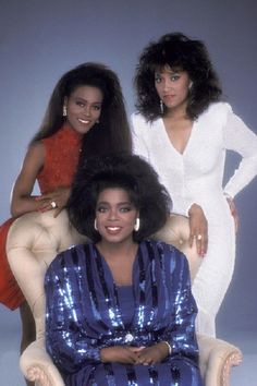 three women sitting on a chair posing for a photo