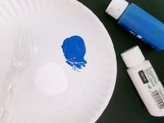 a white paper plate with blue paint on it next to some markers and a fork