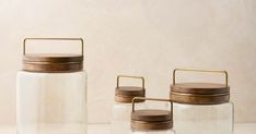 three glass jars with wooden lids on a table