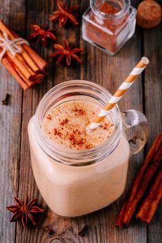 an image of a drink in a glass with cinnamons and spices around it on the table