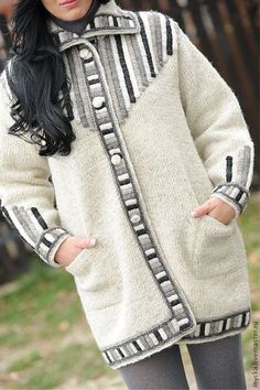 a woman wearing a white coat with black and grey stripes on the front, standing outside