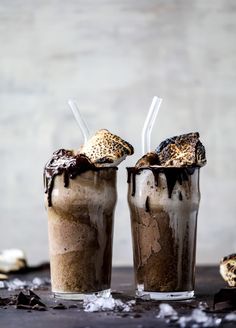 two glasses filled with ice cream and chocolate milkshakes on top of a table