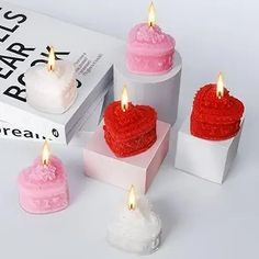 three heart shaped candles sitting on top of a box next to two boxes with frosting