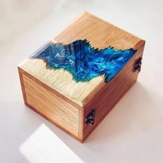 a wooden box with blue and green designs on the lid sitting on a white surface