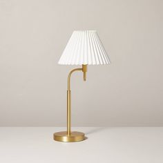 a lamp that is on top of a white table with a beige wall in the background