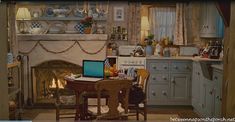 a laptop computer sitting on top of a wooden table in a kitchen next to a fire place