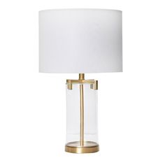 a glass table lamp with a white shade on the base and a gold metal frame