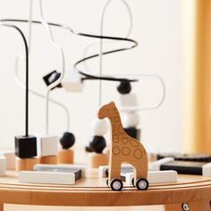 a wooden giraffe toy sitting on top of a table next to a cell phone