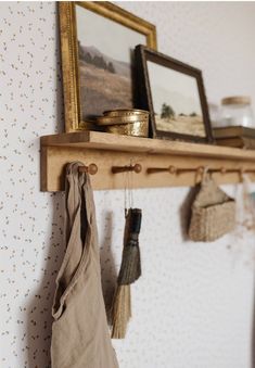 a shelf with some items hanging on it and a mirror over the wall behind it