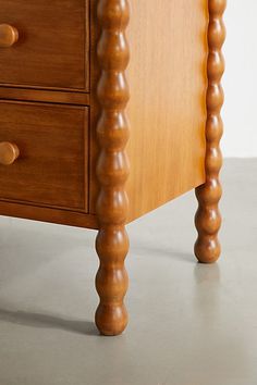 a wooden dresser with three drawers and two knobs