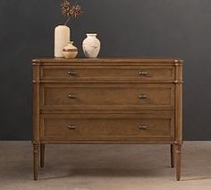 a dresser with two vases on top of it and one flower in the middle