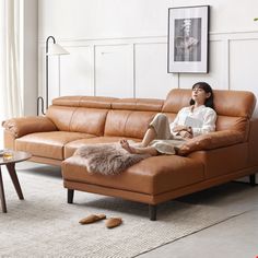 a woman sitting on top of a brown leather couch