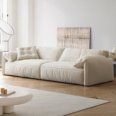 a living room with white furniture and wood flooring on the wooden floor, along with a large window