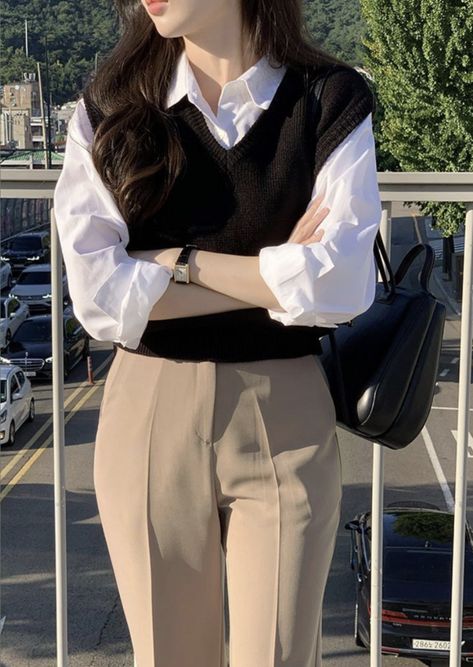 Achieve a timeless and polished look with this classic layered outfit featuring a black knit sweater vest over a crisp white button-down blouse. Paired with tailored beige trousers, casual and sophisticated. Whether for work or a coffee date, this look delivers effortless elegance. Accessorized with a sleek black leather bag and minimalist watch.  #LayeredLook #ClassicOutfit #BusinessCasual #MinimalistFashion #EffortlessChic #OOTD #styleguide Sweater Vest Formal Outfit, T Shirt With Jeans Outfits, Korean Classy Outfits, Korean Work Outfit, Aesthetic Lawyer, Outfit Formal Mujer, Simple Casual Outfits, Casual Work Outfits Women, Lawyer Fashion