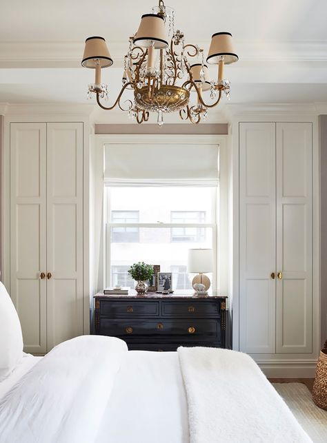 Above the bed is a vintage French chandelier from Chairish, and in front of the window rests a Louis XVI–style black lacquered chest of drawers. To make the space feel brighter and larger, the walls and all the custom millwork were painted in Benjamin Moore’s Snowfall White. Upper East Side Apartment, Built In Dresser, Custom Millwork, Manhattan Apartment, French Chandelier, French Bedroom, Nate Berkus, Elle Decor, Cozy Bedroom