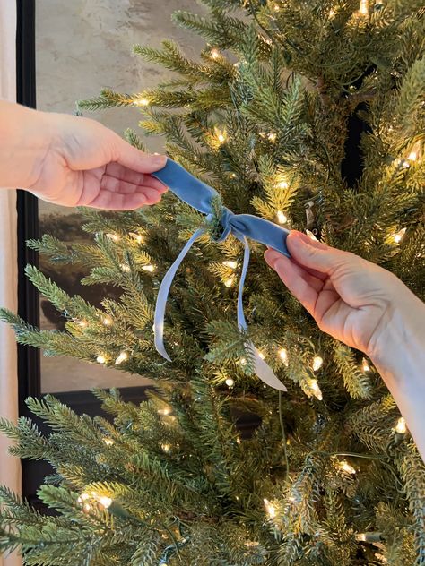 two hands are pulling ribbon from a christmas tree