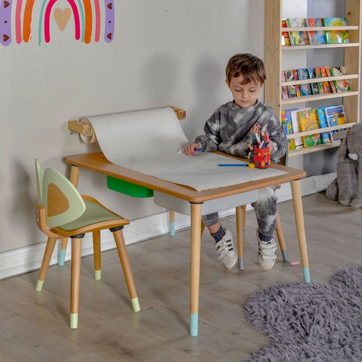 a little boy that is sitting at a table in front of a paper and pen