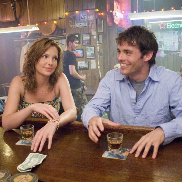 a man and woman sitting at a bar with cards in front of them