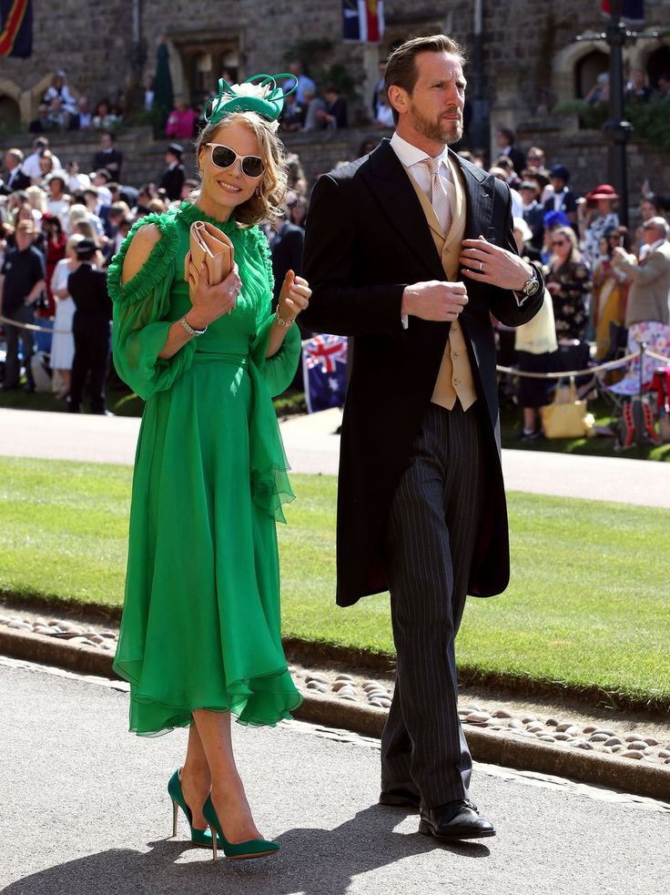 a man in a suit and tie walking next to a woman in a green dress