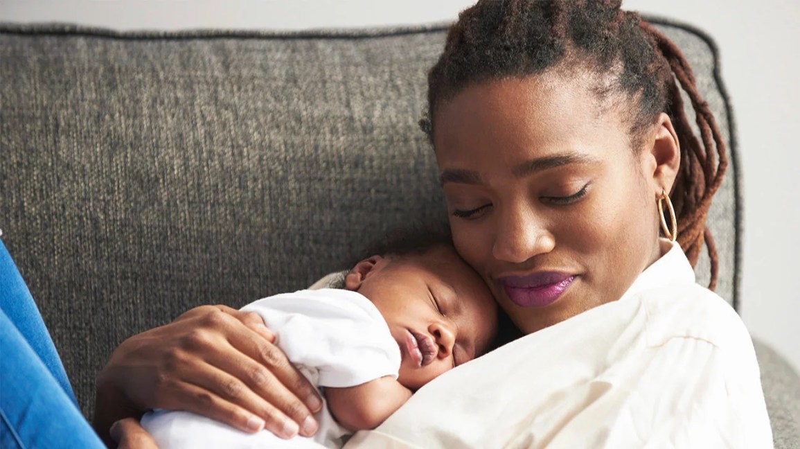 mother cradles newborn on sofa