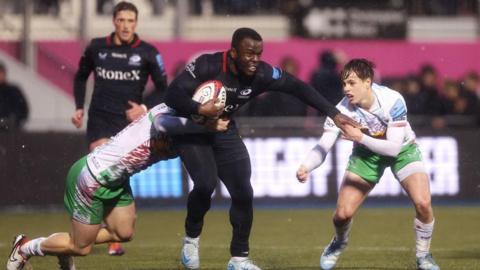 rugby player being tackled by two opponents in wet conditions