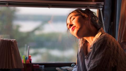 A woman on a train with the sun shining