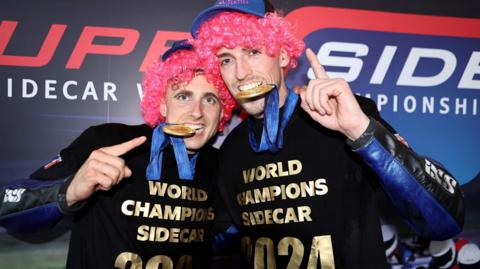 Kevin Rousseau and Harry Payne wearing pink wigs and t-shirts with the slogan 'World Champions Sidecar 2024' 