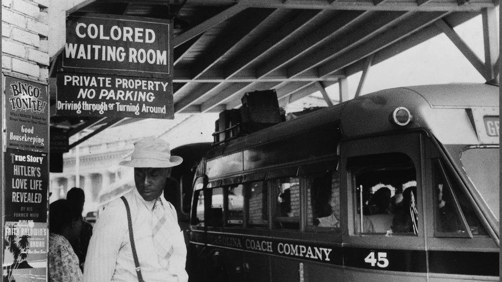 Photo taken at the bus station, showing the Jim Crow signs of racial segregation, Durham, North Carolina, May 1940.