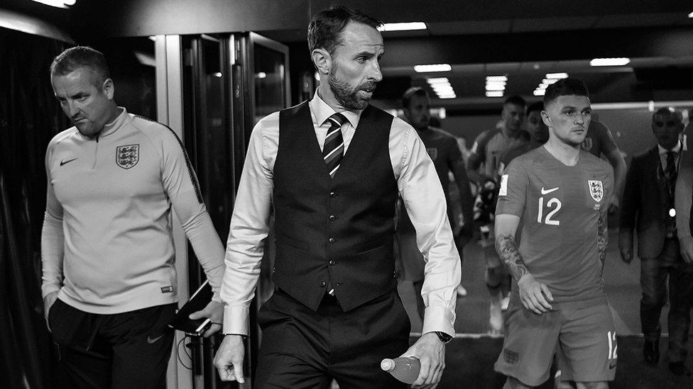 The England manager Gareth Southgate leads his players out of the tunnel. The image is in black and white.