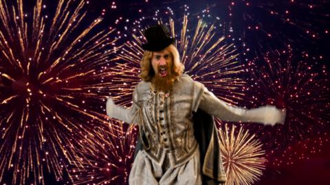 A South Asian man with long brown hair, beard and a black top hat with 17th century clothing, is mid air jumping. Behind him is a sky full of exploding fireworks.