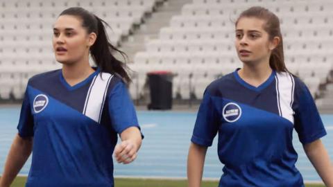 Two characters from Mustangs FC stand side by side on a football field.