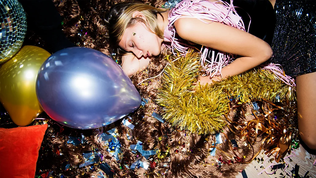 A woman sleeping on the floor, surrounded by the debris from a night of partying (Credit: Getty Images)